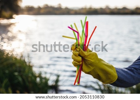 Disposable plastic straw in hand. Water pollution. Global environmental issues