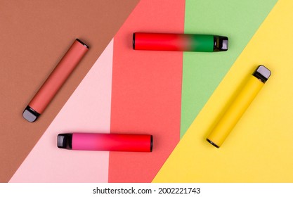 Disposable single pink e-cigarettes with saline nicotine. Pod systems of different colors. Devices for quitting smoking. Red, yellow, green, pink. conceptual fashion photo. Lines and geometry