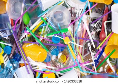 Disposable single use plastic objects such as bottles, cups, forks, spoons and drinking straws that cause pollution of the environment, especially oceans. Top view. - Shutterstock ID 1420338518
