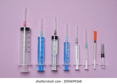 Disposable syringes with needles on violet background, flat lay
