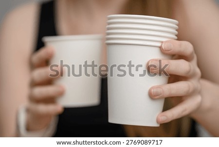 Disposable white drinking cups held in hands, sup