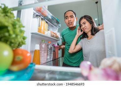 Dissapointed Couple While Opening The Fridge Door