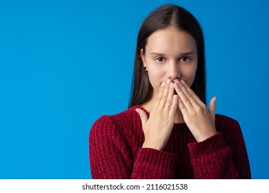 Dissapointed Young Teen Girl Covering Her Mouth Against Blue Background