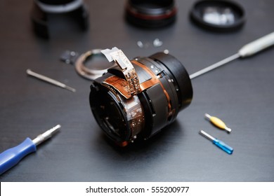 Dissassembled Dslr Camera Lens On Table In Workshop.Service Center Tools,micro Screwdriver Tool Kit To Demount Optical Elemets & Microchips.broken Lense On Table For Service Repairs.Fix Cameras Optics