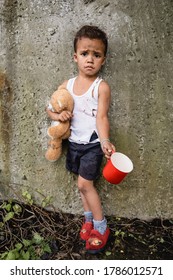 Dissatisfied African American Child In Dirty Clothes Begging Alms Near Concrete Wall In Slum