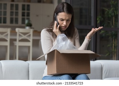 Dissatisfied angry woman, cheated client sit on sofa check received box, damaged or broken goods in parcel, talks to customers support, express complaints, looks annoyed. Bad delivery services concept - Powered by Shutterstock