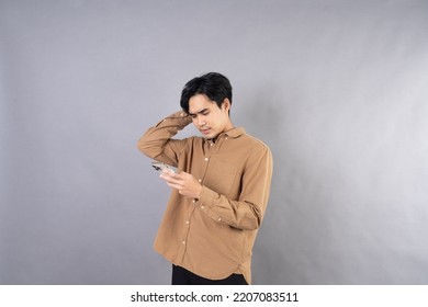 Dissatisfied, Problem With The Phone. An Angry Asian Male Is Enraged By The Poor Performance Of A Smartphone App And The Weak Wifi Signal. 