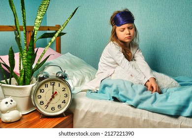 Dissatisfied upset child girl schoolgirl in white pajamas woke up early in the morning, does not want to get up