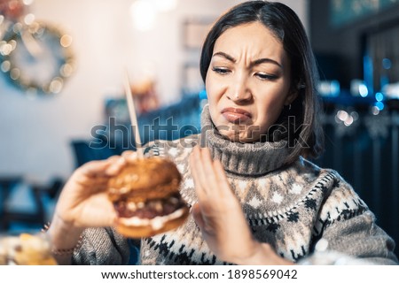 Dissatisfied woman refuses to eat a fat and spicy burger in a restaurant. Perhaps she is a vegetarian or simply stay healthy or has problems with the gastrointestinal tract