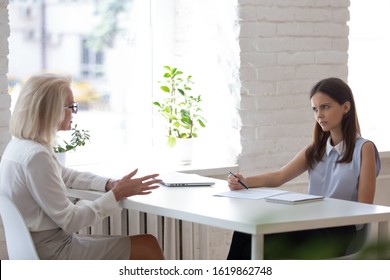 Dissatisfied young HR manager handle job interview with aged 50s woman applicant sitting in front of each other at desk. Concept of inappropriate candidate, age discrimination, unqualified candidature