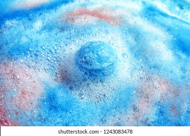 Dissolving color bath bomb in water, closeup