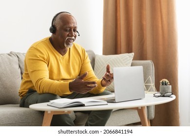 Distance Communication. Senior Black Man Video Calling Talking To Laptop Webcam Working Sitting On Sofa At Home. Mature Male Communicating Online Using Computer And Headphones. Side View - Powered by Shutterstock