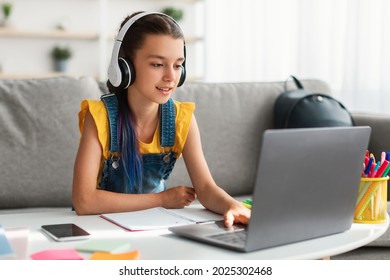 Distance Education Concept. Portrait of female teenager in headphones studying online on pc at home. Youth with dyed coloful hair using laptop to make homework assignment, typing on keyboard - Shutterstock ID 2025302468