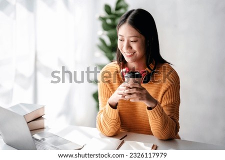 Distance education learning concept, Young woman in sweater studying education lesson online and drinking hot chocolate while watching and learning course through video on laptop at home.