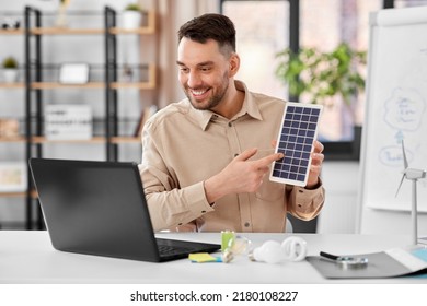 Fernunterricht, Schule und umweltfreundliches Energiekonzept - glücklicher, lächelnder männlicher Lehrer mit Laptop- und Solarakkumulationsmodell mit Online-Klasse im Heimbüro