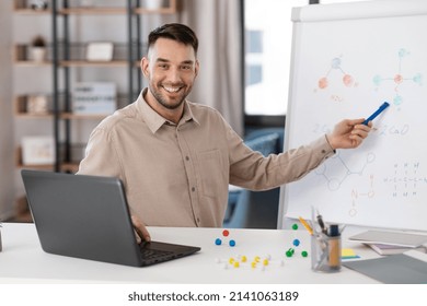 distance education, school and remote job concept - happy smiling male chemistry teacher with laptop computer having online class and showing molecular model on flip chart at home office - Shutterstock ID 2141063189