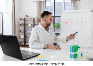 Distance Education, School And Science Concept - Happy Smiling Male Chemistry Teacher With Laptop Computer Having Online Class And Showing Molecular Model On Flip Chart At Home Office