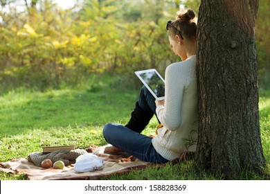 Educação à distância. Mulher sentada usando tablet durante passeio ao ar livre