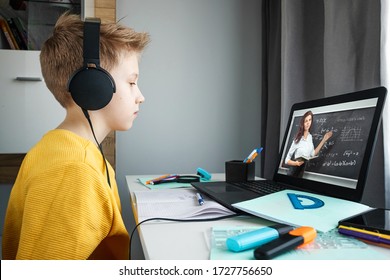 Distance learning, a boy in headphones sits at a table at home looking in a beech laptop. The concept of online education, home education, technology, school