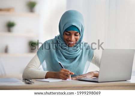 Distance Learning Concept. Smiling Black Islamic Woman In Hijab Study With Laptop At Home, African Muslim Lady Taking Notes While Having Online Lesson On Computer, Enjoying Remote Education