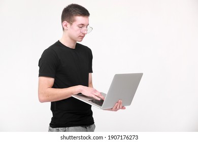 Distance Learning Online Education. Portrait Of A Young Man In A Black T-shirt With Glasses With A Laptop On A White Background. Copy Space.