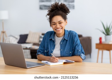 Distance learning, online education. Portrait of smiling young female freelancer working in co-working, modern office or home. African American woman using laptop computer looking at camera, smiling - Shutterstock ID 2125113236