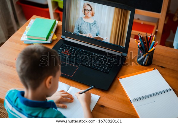 Distance\
learning online education. A schoolboy boy studies at home and does\
school homework. A home distance\
learning.