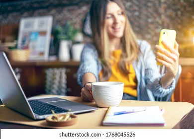 Distance learning online education and work. Business woman having a facetime video call. Happy and smiling girl working from home office kithcen and drinking coffee. Using computer and mobile phone