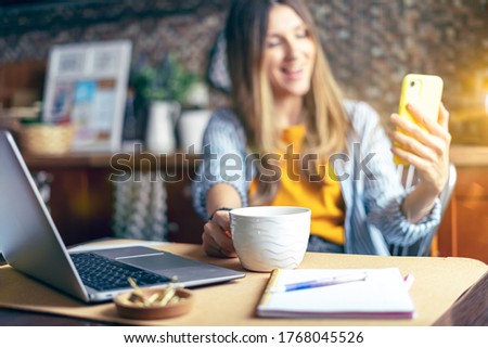Distance learning online education and work. Business woman having a facetime video call. Happy and smiling girl working from home office kithcen and drinking coffee. Using computer and mobile phone