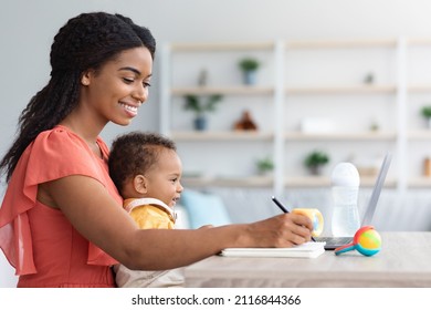 Distance Learning. Smiling Black Woman With Baby Study Online On Laptop At Home, Happy African American Mother Using Laptop For Remote Education, Watching Webinar And Writing Notes In Notepad - Shutterstock ID 2116844366