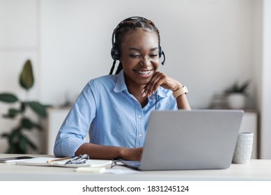 Distance Learning. Young African American Woman In Headset Watching Webinar On Laptop Computer, Sitting At Desk In Office, Having Online Business Training, Enjoying Internet Education, Copy Space