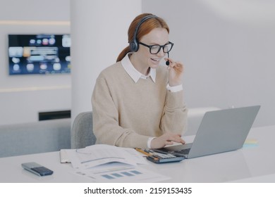 Distance Online Interpreter. Positive Young Woman Is Consultant Of Call Center. Friendly Girl In Headset Is Talking To Client At PC In Office. Service And Customer Support Concept.