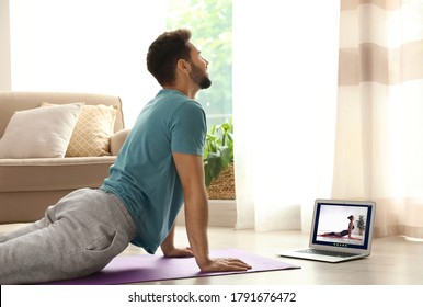 Distance Yoga Course During Coronavirus Pandemic. Man Having Online Practice With Instructor Via Laptop At Home