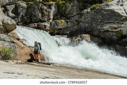 Distant Backpacker Stands In Front Of Cascade Fall Along The Merced River In Yosemite National Park