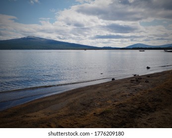 Distant blue mountain with big dramatic sky over beautiful lake shore.  