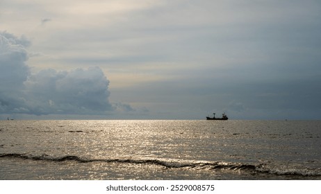 Distant cargo ship sailing on a calm sea under a cloudy sky with soft waves in the foreground. Peaceful maritime scene with serene atmosphere and soft lighting. - Powered by Shutterstock