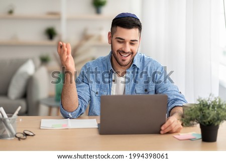 Distant Communication Concept. Portrait of happy jewish male in yarmulke and casual shirt making video call sitting at desk at home office and talking with colleagues, students or family, explaining ストックフォト © 