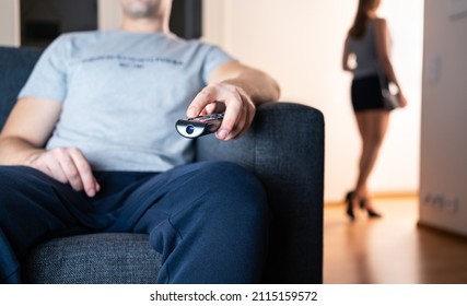 Distant couple ignore each other. Relationship fight, crisis or quarrel. Antisocial boring lazy man watching tv. Lonely sneaky woman leaving to party or cheat with secret lover. No common interests.