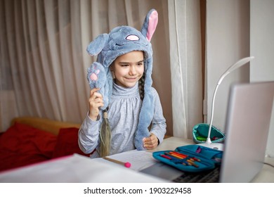 Distant Education, Online Class Meeting. Pretty Schoolgirl Wearing Funny Rabbit Hat With Ears To Amuse Classmates During Boring Online Lesson At Home, Social Distance During Quarantine, Self-isolation