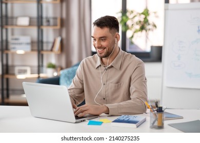 distant education, school and remote job concept - happy smiling male teacher with laptop computer and wireless earphones working at home office