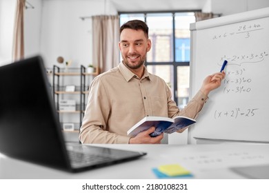 Fernunterricht, Schule und fernes Arbeitskonzept - glücklicher, lächelnder Mathematiklehrer mit Laptop-Berechnung und Buch-Gleichung auf Flip-Chart mit Online-Unterricht oder Videoanruf im Heimatbüro