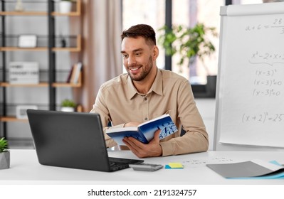 Distant Education, School And Remote Job Concept - Happy Smiling Male Math Teacher With Laptop Computer, Book And Flip Chart Having Online Class Or Video Call At Home Office