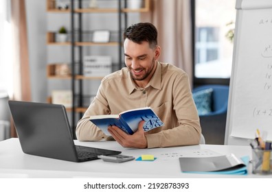 Distant Education, School And Remote Job Concept - Happy Smiling Male Math Teacher With Laptop Computer, Book And Flip Chart Having Online Class Or Video Call At Home Office