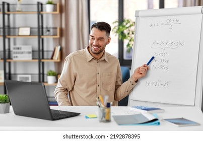 Distant Education, School And Remote Job Concept - Happy Smiling Male Math Teacher With Laptop Compute Showing Equation On Flip Chart Having Online Class Or Video Call At Home Office