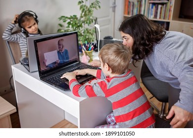 Distant Home Education, Children Doing Homework And Mother Working And Help Them. Elementary School Kids During Online Class With Parent Working Remotely In One Room, Self-isolation, Focus On Boy