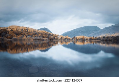 Distant Mountains Form Symmetrical Reflections In Clean Lake Water