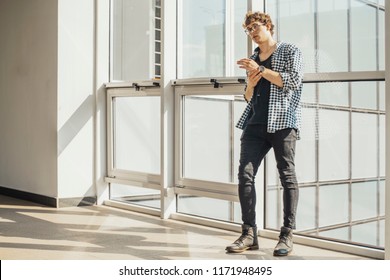 Distant plan of young man standing next to big windows at metro station.
