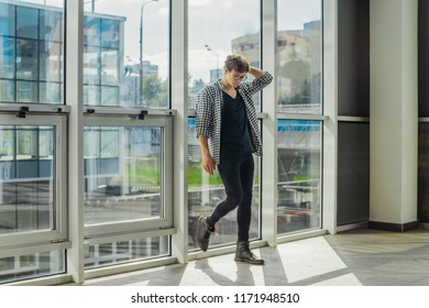 Distant plan of young man standing next to big windows at metro station.