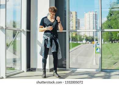 Distant plan of young man standing next to big windows at metro station.