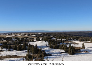 Distant ranch dots a forested valley from a mountain overlook